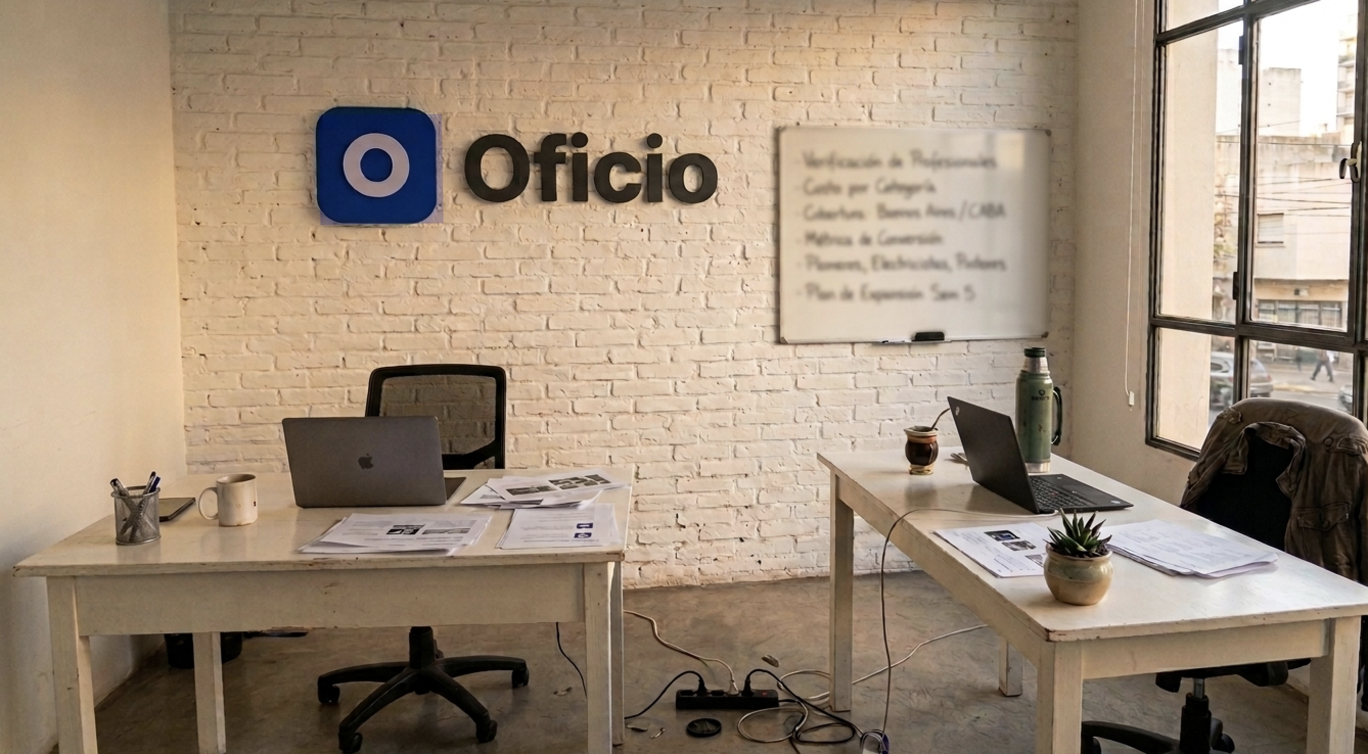 Visión de la oficina de Oficio — pizarra con plan de expansión por barrio y escritorios del equipo